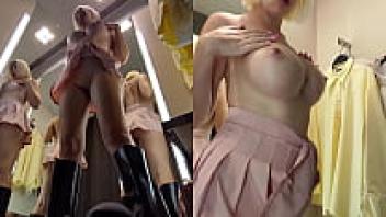 Upskirt view of a blonde's large tits in a public changing room