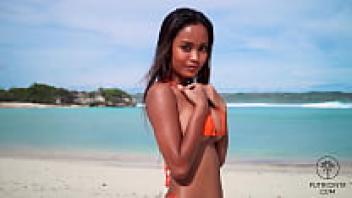 At a stunning tropical beach, Putri Cinta is stripping.