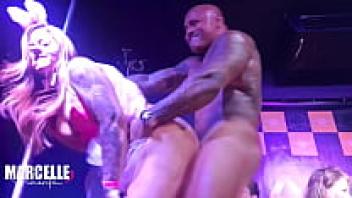 A group of girls on a nightclub stage having sex with a stripper